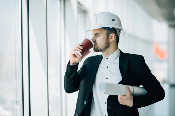 Arkitekten mannen hålla ritningar, ingenjör inspektion i arbetsplatsen för arkitektoniska plan, byggprojekt på bakgrunden panoramautsikt över byggnaden skyskrapor. — Stockfoto