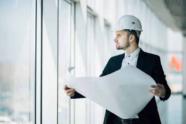 Närbild av ingenjörer som arbetar på en byggarbetsplats som innehar en ritningar. Teknik och arkitektur koncept — Stockfoto