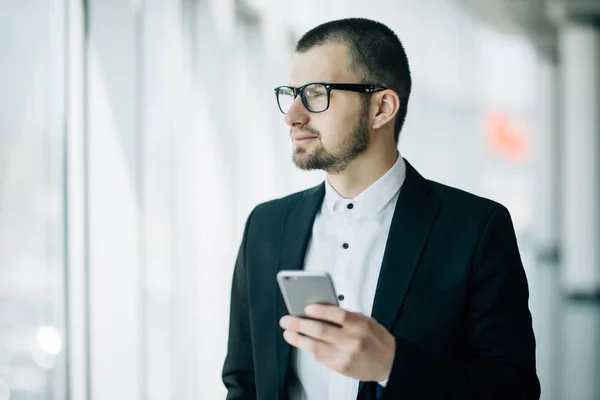 Obchodní muž použití na mobil hovor stál v popředí panoramatické okno — Stock fotografie