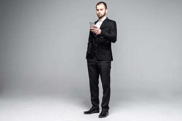Ung affärsman att skriva meddelande på smartphone pekskärm. Hela kroppen längd porträtt isolerade över vita studio bakgrund. — Stockfoto