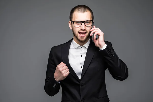 Empresário feliz falando ao telefone e celebrando seu sucesso sobre fundo cinza — Fotografia de Stock