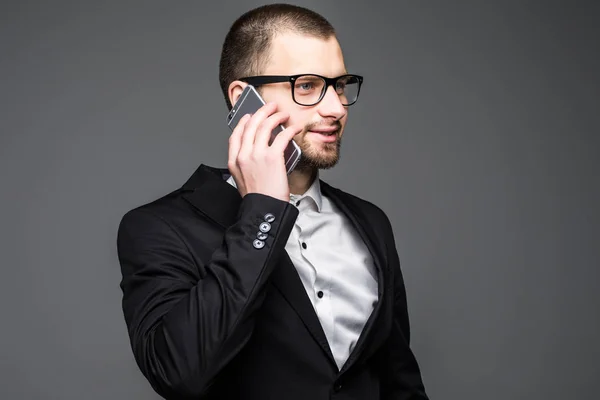 Portrait of a businessman speaking on cell phone isolated on a gray background — Stock Photo, Image