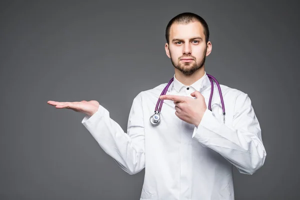 Mladý doktor s otevřenou ruku dlaní na šedém pozadí — Stock fotografie
