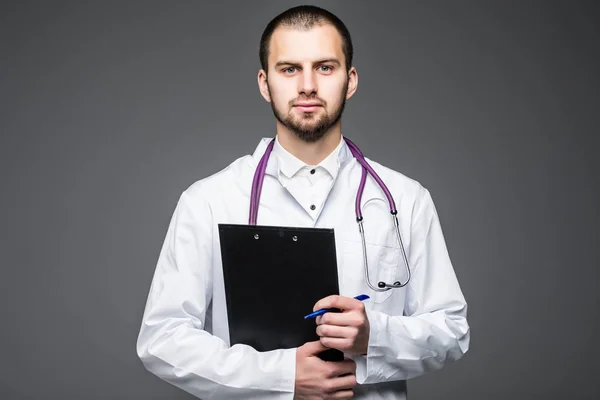 Portrét mladého lékaře pohledný muž držící prázdné izolované na šedém pozadí — Stock fotografie