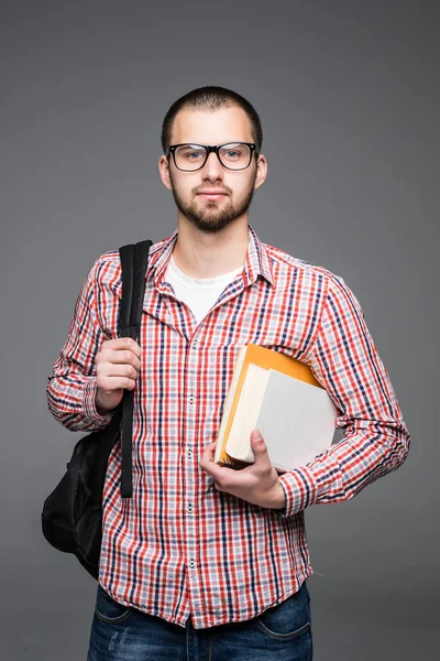 Веселый молодой человек с рюкзаком ходить и держа книги на белом фоне — стоковое фото
