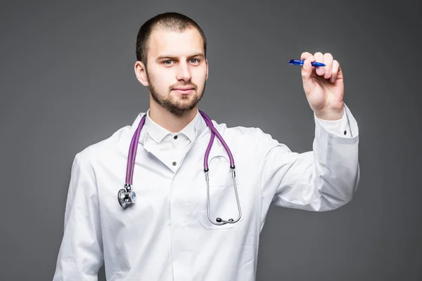 Young male doctor writing something on screen isolated over a gray background — Stock Photo, Image
