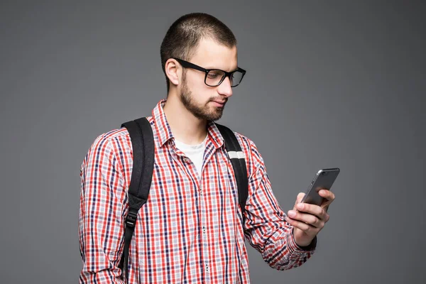 Un joven estudiante escribiendo un mensaje de texto en un teléfono móvil aislado sobre un fondo blanco — Foto de Stock