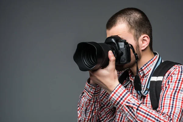 Portrait of photographer taking pictures with digital camera isolated on gray background