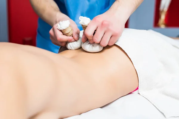 Retrato de joven hermosa mujer en el salón de spa recibe masaje con bolas de hierbas de spa — Foto de Stock