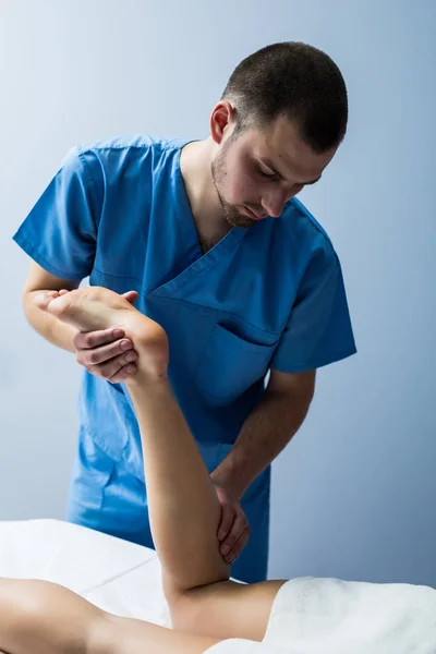 Dettaglio delle mani massaggiando il muscolo del polpaccio umano. ManTherapist applicando pressione sulla gamba femminile . — Foto Stock