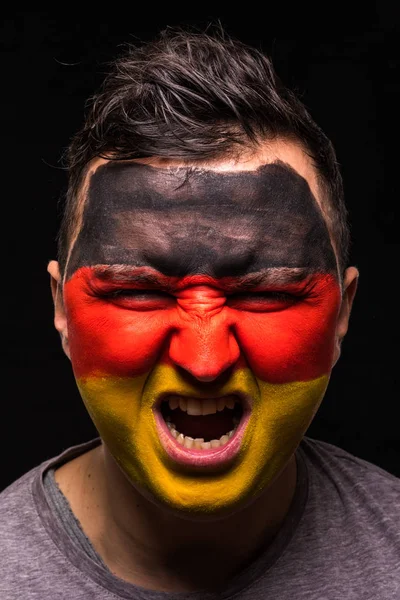 Retrato de hombre guapo partidario de la cara fan de la selección nacional de Alemania con la cara de la bandera pintada aislado sobre fondo negro. Aficionados emociones . — Foto de Stock