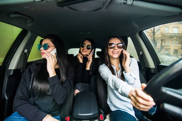 Троє молодих жінок друзі розмовляють в машині розмовляють по телефону — стокове фото