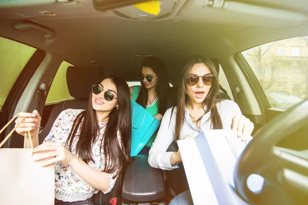 Młodych kobiet powracających z zakupy wewnątrz samochodu. Młode dziewczyny, jazda samochodem i wracając z zakupów. — Zdjęcie stockowe