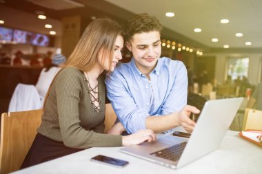 Mutlu çift konuşmak ve kafede dizüstü bilgisayar kullanarak