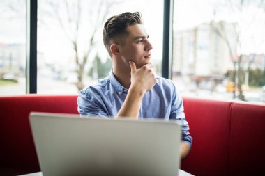 Yakışıklı genç erkek girişimci kafede otururken dizüstü