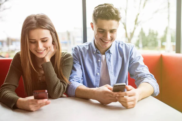 Adicción digital. Atractiva pareja agradable citas mientras sostiene los teléfonos y mirando fijamente — Foto de Stock