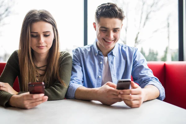 Jong koppel in café kijken naar hun smartphones, sociaal netwerk concept — Stockfoto