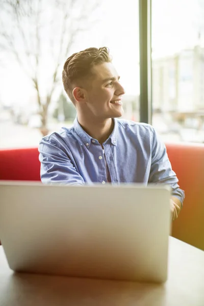 Guapo joven empresario masculino en el ordenador portátil mientras está sentado en la cafetería —  Fotos de Stock