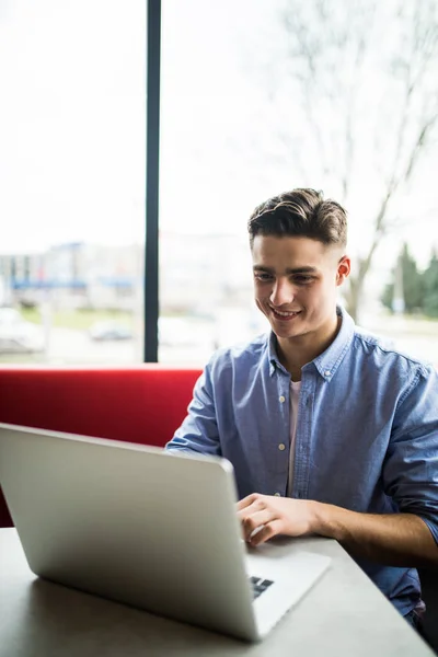 Relaxé jeune professionnel surfer sur Internet sur son ordinateur portable dans un café — Photo