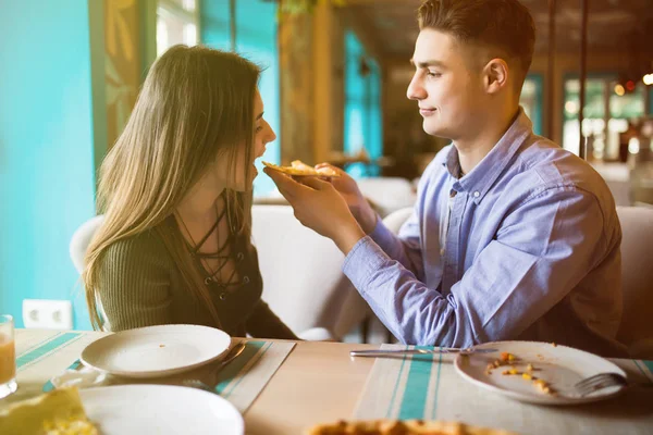 No amor Casal comer pizza em casa e sorrindo. Eles estão compartilhando pizza em um café interior . — Fotografia de Stock