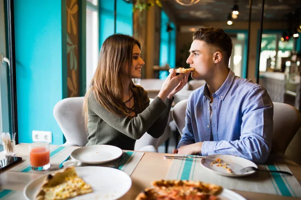 Randki w pizzerii. Przystojny uśmiechający się para udostępnianie i oglądanie w pizza, wspólna zabawa. — Zdjęcie stockowe
