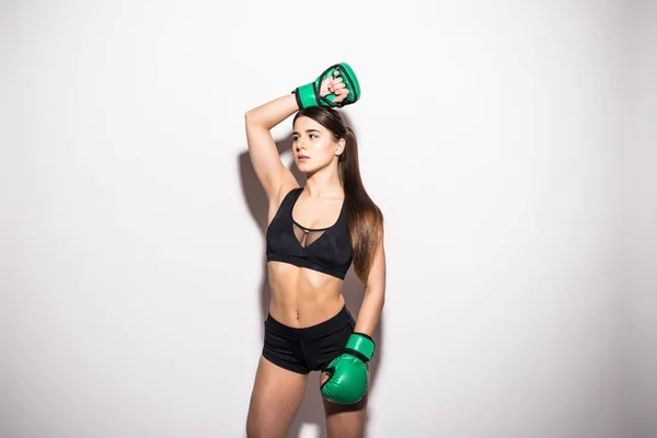 Portrait of a confident young athlete woman posing in green boxing gloves isolated over white background — Stock Photo, Image