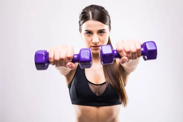 Mujer deportiva hace los ejercicios con pesas sobre fondo blanco. Mujer joven en ropa deportiva sobre fondo blanco. Fuerza y motivación . — Foto de Stock