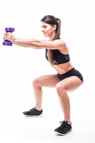 Mladá sportovní svalnatá žena dělá dřepy izolované na bílém pozadí. Žena v sportovní oblečení provádění cvičení — Stock fotografie