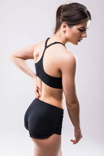 Vista trasera de una mujer joven con dolor espinal aislado sobre fondo blanco — Foto de Stock