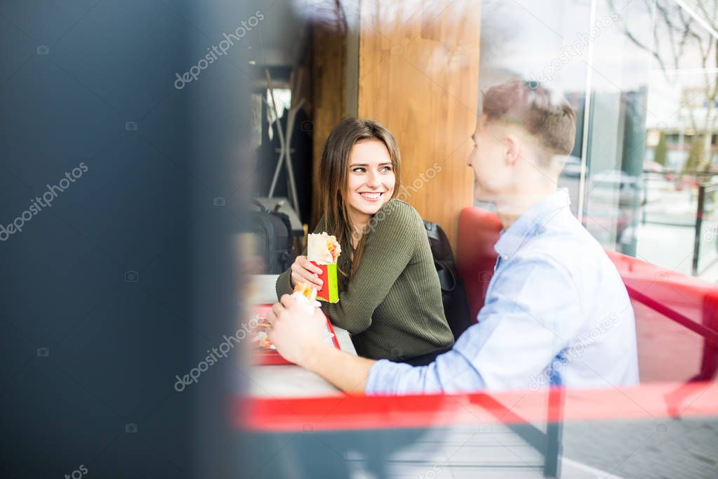 Couple in love hugging having fun, laughing and smiling together. Handsome boyfriend joke of her girlfriend and feed her, french fries.