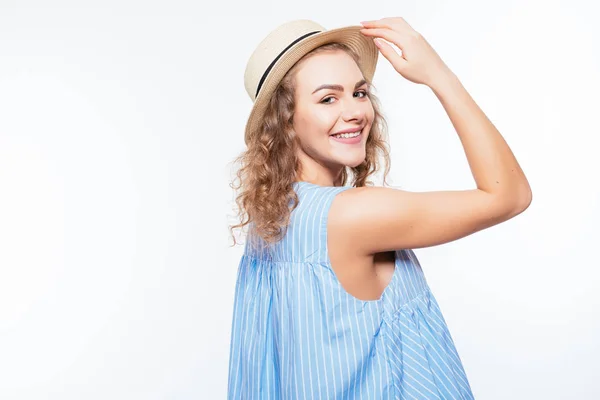 Retrato de una mujer atractiva sonriente en vestido de verano y sombrero posando mientras está de pie y mirando a la cámara aislada sobre fondo blanco —  Fotos de Stock