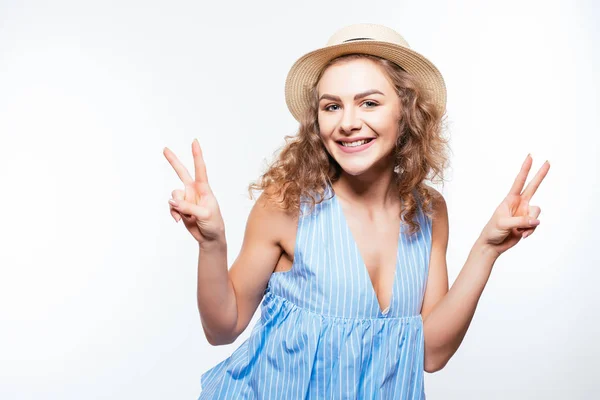 Retrato de una feliz chica alegre en sombrero de verano mostrando gesto de paz con dos manos aisladas en blanco —  Fotos de Stock