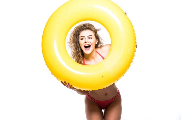 Retrato de una chica feliz vestida con traje de baño mirando a través de un anillo inflable aislado sobre fondo blanco — Foto de Stock