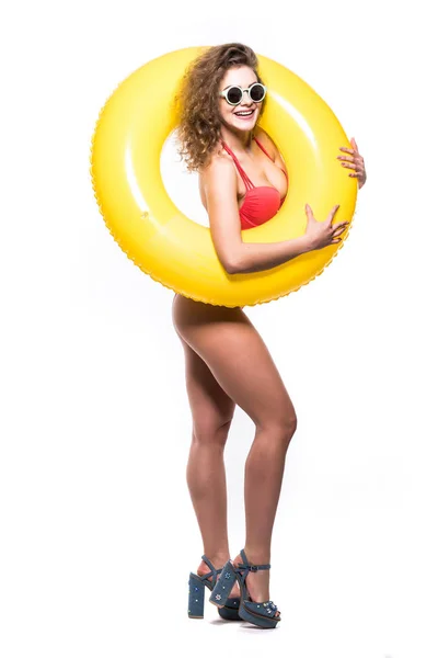 Retrato de longitud completa de una chica feliz vestida con traje de baño en gafas de sol posando con anillo inflable mientras está sobre fondo blanco — Foto de Stock