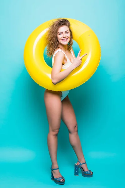 Retrato de longitud completa de una chica sonriente vestida con traje de baño posando con anillo inflable aislado sobre fondo azul —  Fotos de Stock