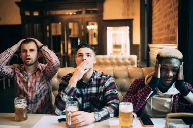 Yakışıklı arkadaş üzgün bira içip pub spor takımı için tezahürat yaparken oturuyor. Bir kulüp veya natioanal takım erkek hayranları