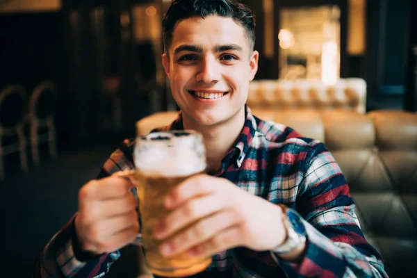 Um homem a beber cerveja. Jovem bonito bebendo cerveja enquanto estava sentado no balcão do bar — Fotografia de Stock