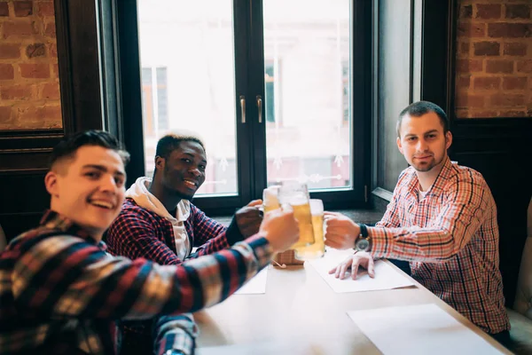 Homens bonitos aplausos estão falando e sorrindo enquanto descansam no pub — Fotografia de Stock