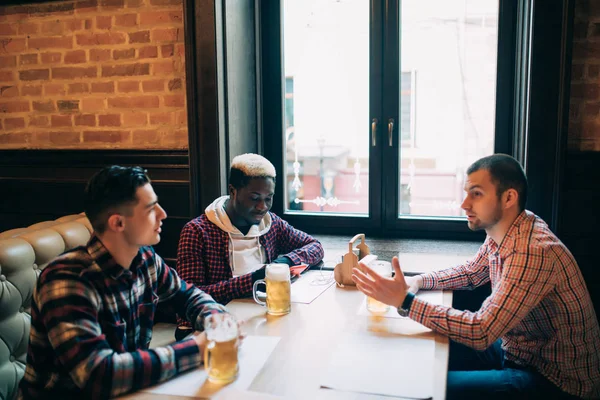 Amigos multirraciais conversando e bebendo cerveja e copos no pub — Fotografia de Stock