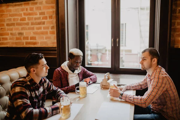 Amigos multirraciais conversando e bebendo cerveja e copos no pub — Fotografia de Stock