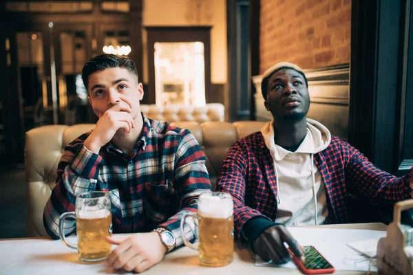 Boos mannelijke vrienden kijken naar sport spel of voetbalwedstrijd en drinken bier bij bar of pub — Stockfoto