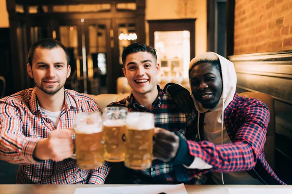 Människor, män, fritid, vänskap och fest koncept - happy manliga vänner dricka öl och spottar glasögon på baren eller pub — Stockfoto