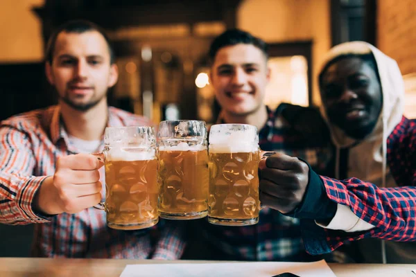 Grupo de amigos multirraciales que beben cerveza y vasos tintineos en el bar o pub — Foto de Stock