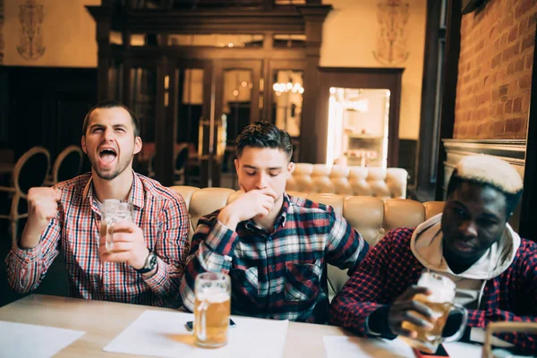 Jovens amigos homens bonitos alegres se divertindo no pub de cerveja assistindo jogo na TV apoiar diferentes equipes com emoções felizes ou tristes — Fotografia de Stock