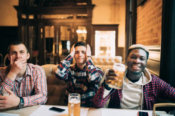 Jovens amigos homens bonitos alegres se divertindo no pub de cerveja assistindo jogo na TV apoiar diferentes equipes com emoções felizes ou tristes — Fotografia de Stock