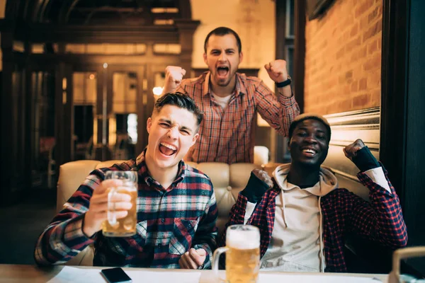 Overwinning. Groep jonge mooie vrienden, Tv kijken en juichen voor hun team tijdens het rusten in de pub. — Stockfoto