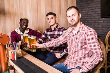 Eğleniyor ve pub bar sayacı, fıçı bira içme neşeli çok ırklı eski dostlar.