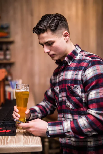 Jovem com garrafa de cerveja usando telefone no balcão no pub — Fotografia de Stock