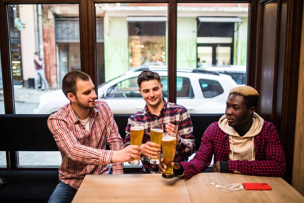 Jovens felizes homens multirraciais amigos beber cerveja e falar no pub — Fotografia de Stock