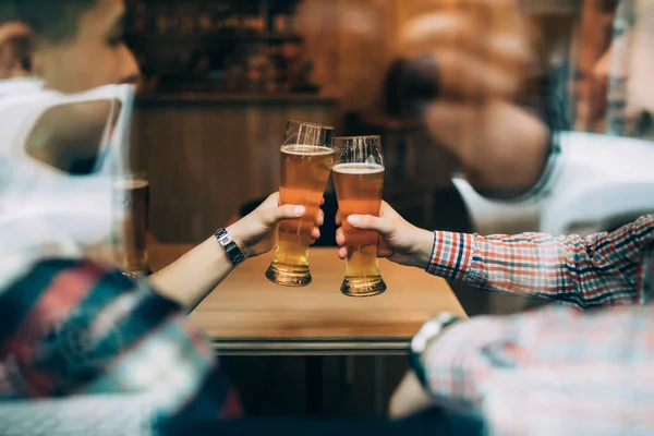 Nära håll händerna på vänner som sitter på de puben cheers med öl glasögon tråg fönster. — Stockfoto